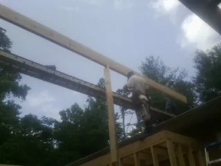 Carpenter setting a ridge beam over a new addition frame — Ice Dam Removal by Roofing Brothers in Cody