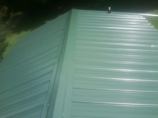 New green metal panels meeting at the ridge of a roof — Flat Roof Repair work by our crew in Cody