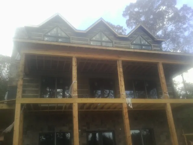 Dormers and porch framing on a large log home under construction — Roof Coating work by our crew in Cody