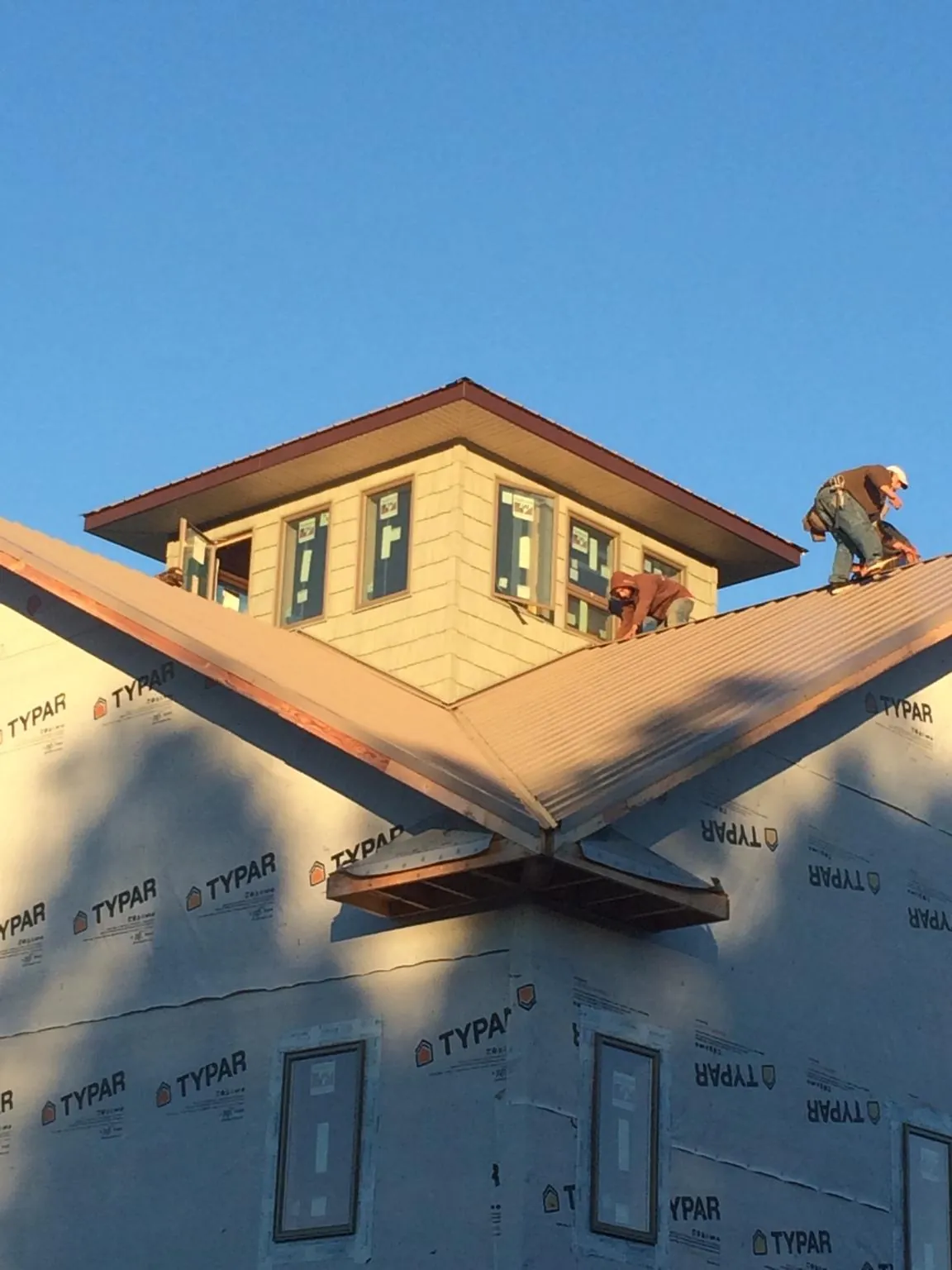 Roofers working around a rooftop cupola on a new metal roof at sunset — Roof Waterproofing in Cody by Roofing Brothers